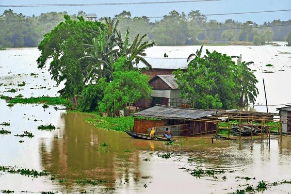 An Assam home cut off by floodwater with a small boat moored beside it